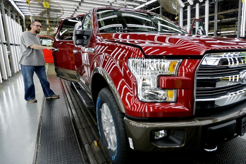 FILE - A worker inspects a new aluminum-alloy body Ford F-150 truck at the company's Kansas...