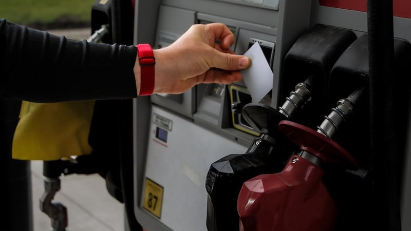 Person tapping credit card onto a gas station payment reader.