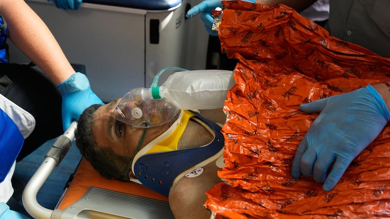 Rescue workers attend to Hernán Alberto Gil Flores after he was pulled from the rubble eight...